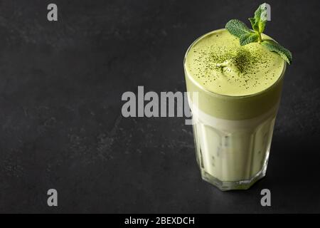 Verre de thé Dalgona Icé Matcha . Lait froid et thé matcha fouetté avec des œufs blancs isolés sur noir. Espace pour le texte. Banque D'Images