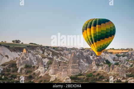 un ballon d'air chaud aux couleurs vives au-dessus des maisons de la grotte de cappadoce Banque D'Images