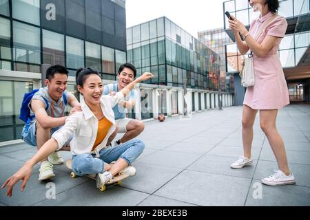 Le jeune homme pousse la femme classmate assis sur un skateboard Banque D'Images