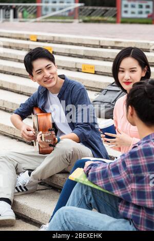 Les jeunes étudiants de l'université ont pris la mesure de jouer de la guitare pour chanter Banque D'Images