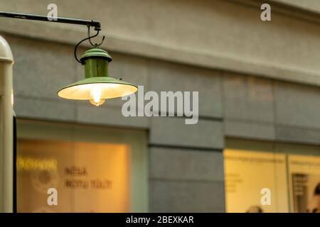 Lampe à ampoule Edison suspendue devant la fenêtre avec la vieille ville derrière. Vertical. Banque D'Images