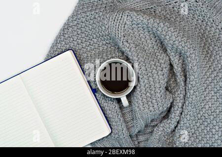 Plat de travail confortable de l'écriture avec le café chaud du sweat, le papier à note et les accessoires d'écriture. Travail à la maison. Écriture. Concept chaud dans le froid Banque D'Images