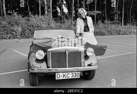 Victoria Voncampe, deutsche Fernsehansagagin, Moderatorin und Schauspielerin, mit ihrem kleinen Fiat Cabrio, Deutschland um 1969. Présentateur de télévision allemande, hôte et actrice Victoria Voncampe avec sa minuscule Fiat convertible, Allemagne vers 1969. Banque D'Images