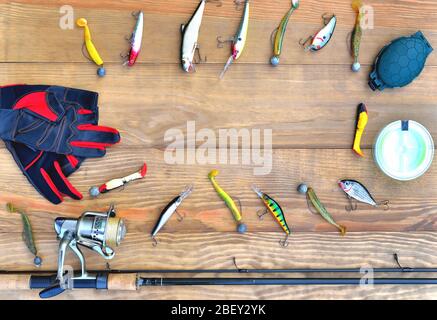 accessoires de pêche, baguette de pêche, bobine avec ligne de pêche, appâts et lures en silicone, gants de patinage et boîte d'accessoires sur fond en bois, gros plan, Banque D'Images