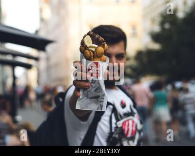 Jeune homme tenant une gaufres à bulles avec crème glacée et chocolat. Gaufre aux fruits, au chocolat et à la glace Banque D'Images