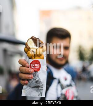 Jeune homme tenant des gaufres avec de la glace, des bananes et du chocolat Banque D'Images