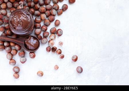 Chocolat et noisettes faits maison frais, répartis sur une toile de fond en marbre blanc. Profondeur de champ extrêmement faible avec fond flou. Banque D'Images