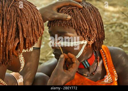 Les tribéshommes de Hamer appliquent de la peinture faciale avant le début d'une cérémonie tribale. Photographié dans la vallée de la rivière Omo, en Ethiopie Banque D'Images