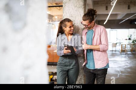 Des personnes heureuses qui parlent et naviguent sur Internet pendant une pause sur le lieu de travail Banque D'Images