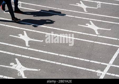 16 avril 2020, Rhénanie-du-Nord-Westphalie, Düsseldorf: Les piétons jettent leur ombre à côté de pictogrammes sur les pavés le long des rives du Rhin. La vie publique est encore limitée par la crise du coronavirus. Photo: Federico Gambarini/dpa Banque D'Images