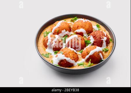 Malai Kofta Curry dans un bol noir isolé sur fond blanc. Malai Kofta est un plat de cuisine indienne avec des pommes de terre et des boulettes de paneer frits en oni Banque D'Images