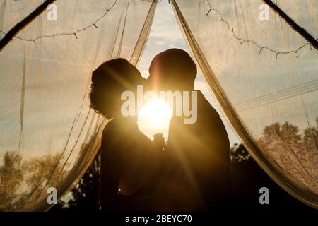 Un baiser romantique de la mariée et marié contre le coucher du soleil. Leur amour durera pour toujours. Banque D'Images