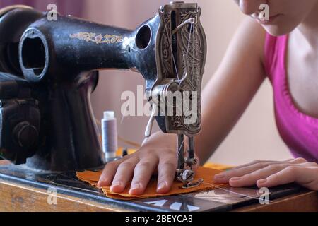 Une jeune couturière cousue à la maison sur une ancienne machine à coudre rétro. Les mains sont sur le tissu. Processus de couture rapprochée. Profondeur de champ peu profonde. Banque D'Images