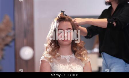 Fille coiffeur faire la coiffure sous forme de cheveux tournoyants. Banque D'Images