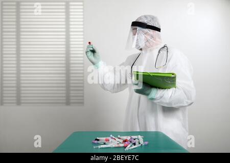 Médecin portant un masque respiratoire et tenant l'échantillon sanguin de Covid-19 de Coronavirus. Médecin travaillant avec des échantillons de sang dans un laboratoire hospitalier Banque D'Images