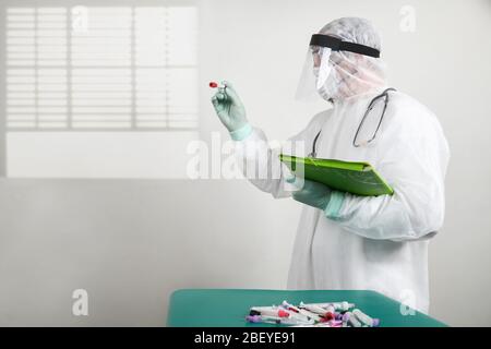 Médecin portant un masque respiratoire et tenant l'échantillon sanguin de Covid-19 de Coronavirus. Médecin travaillant avec des échantillons de sang dans un laboratoire hospitalier Banque D'Images