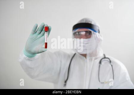 Médecin portant un masque respiratoire et tenant l'échantillon sanguin de Covid-19 de Coronavirus. Médecin travaillant avec des échantillons de sang dans un laboratoire hospitalier Banque D'Images