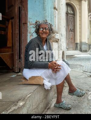 Femme senior assise dans une rue Havanan dans la vieille ville de la Havane avec des lunettes à lentille épaisse et une vue médiocre, mais apparemment content, Cuba Banque D'Images