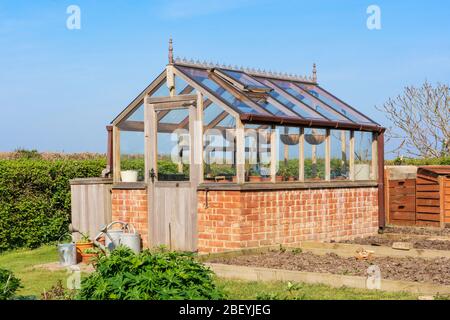 Serre en bois et en brique sur mesure dans un jardin de campagne. Beaucoup Hadham, Hertfordshire. ROYAUME-UNI Banque D'Images