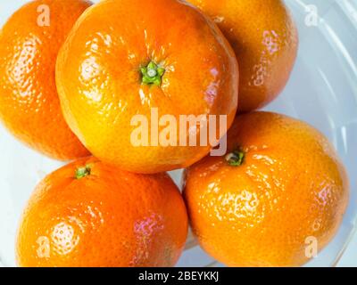 Orange mandarine facile à épluler dans un bol en verre sur fond blanc Banque D'Images