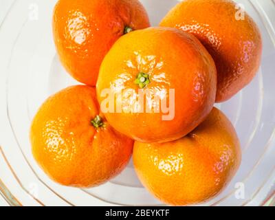 Orange mandarine facile à épluler dans un bol en verre sur fond blanc Banque D'Images