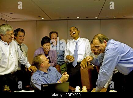 Le président Barack Obama rit des aides à bord d'Air Force One en route vers Singapour, le 14 novembre 2009. Banque D'Images