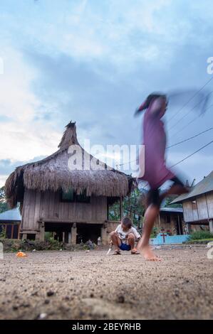 Kelimutu, East Nusa Tenggara / Indonésie - 13 janvier 2015 : enfants jouant devant la maison indonésienne traditionnelle du village de Koanara. Banque D'Images