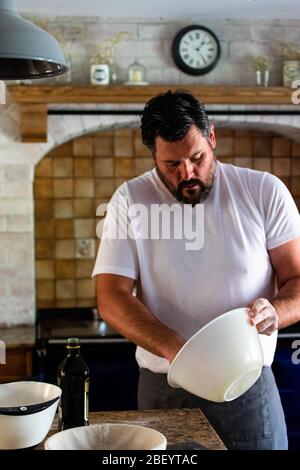 Portrait photographie d'un homme préparant du pain de levain cuit maison dans sa cuisine de ferme, équipé d'un AGA bleu marine Banque D'Images