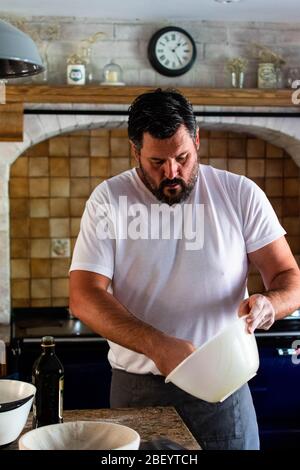 Portrait photographie d'un homme préparant du pain de levain cuit maison dans sa cuisine de ferme, équipé d'un AGA bleu marine Banque D'Images