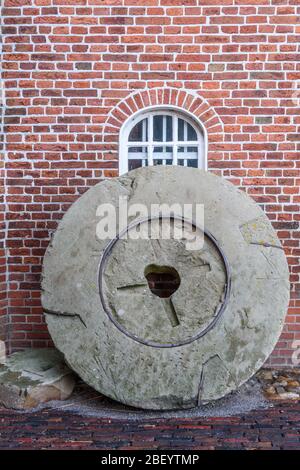 Ancienne pierre de moulin penchée contre un mur, Jemgum Mill, Frise orientale, Basse-Saxe, Allemagne Banque D'Images