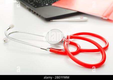 Rendez-vous avec un médecin. Thermomètre, stéthoscope rouge et documents médicaux sur le lieu de travail des médecins au bureau de la clinique. Concept médecine soins de santé Banque D'Images