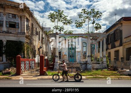 Homme poussant une livraison trike au-delà des ruines de vieux bâtiments coloniaux la Havane avec un panneau en espagnol disant ne pas détritus, Calle 17, la Havane Cuba Banque D'Images