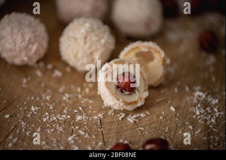 Chocolat blanc aux bonbons maison, noix de coco et noisettes sur une tranche de bois. Boule de neige aux truffes de bonbons Banque D'Images