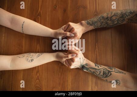 Couple caucasien aimant tenant les mains près sur fond de bois. Romantique, amour, relation, toucher tendre. Soutien et aide à la main, à la famille, au chaud. L'unité, le sentiment et les émotions. Banque D'Images