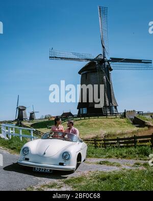 Schermerhorn Alkmaar Pays-Bas avril 2020. Couple faisant un voyage sur route avec une ancienne voiture de sport vintage White Porsche 356 Speedster, moulin à vent néerlandais Banque D'Images