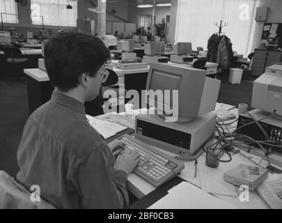 1987, un journaliste masculin utilisant un ordinateur personnel (PC) dans un bureau de journal, avec PCS vu sur la plupart des bureaux. Les éditeurs de journaux ont été l'une des premières industries à voir le potentiel des PC pour rendre leur production plus efficace et rentable par rapport à l'ancienne méthode de composition des métaux à forte intensité de main-d'œuvre. Banque D'Images