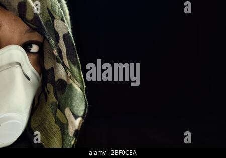 Photo conceptuelle d'une femme guerrière portant un masque FPPP 3 et un casque camouflage. Guerre biologique. Arme létale de coronavirus. Focalisation sélective sur Banque D'Images