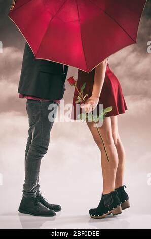 Petite amie et petit ami ayant un baiser passionné caché derrière le parapluie Banque D'Images