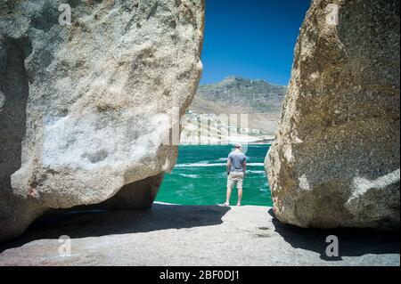 Un homme regarde la belle vue sur la plage de Llandudno, le Cap, la Province du Cap occidental, Afrique du Sud, qui est un endroit populaire pour les surfeurs. Banque D'Images