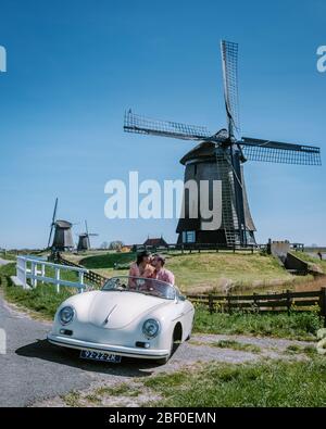 Schermerhorn Alkmaar Pays-Bas avril 2020. Couple faisant un voyage sur route avec une ancienne voiture de sport vintage White Porsche 356 Speedster, moulin à vent néerlandais Banque D'Images