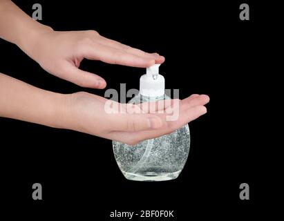 Les mains des femmes appuient une goutte de désinfectant à base d'alcool hors d'un distributeur de savon liquide pour l'appliquer. Moyen de désinfection et d'hygiène antibactériennes. Banque D'Images