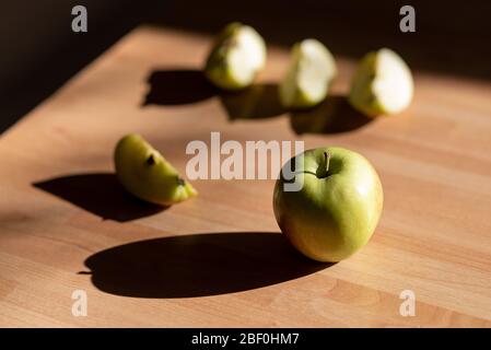 Braeburn pomme sur un panneau en bois avec lumière du soir et ombre Banque D'Images