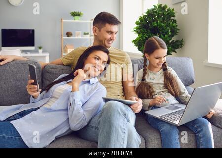Une famille heureuse utilise un ordinateur portable ensemble tout en étant assise à la maison. Banque D'Images