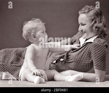 ANNÉES 1930 FILLE BLONDE DANS UN TABLIER EN TISSU S'ASSEOIR JUSQU'À TOUCHER SOURIRE MÈRE INCLINANT PORTANT POLKA DOT ROBE - B1631 HAR001 BÉBÉ HARS TOUCHER FORTE FAMILLE HEUREUSE JOIE VIE SATISFACTION FEMMES STUDIO TIR SANTÉ MAISON VIE COPIE ESPACE AMITIÉ DEMI-LONGUEUR FILLES PERSONNES SOIGNANTES B&W DOT BONHEUR GAI DÉCOUVERTE POLKA POLKA POINTS FIERTÉ JUSQU'À ATTEINDRE SOURIRES CONNEXION POLKA DOT JOYEUSE ÉLÉGANT ATTACHEMENT PERSONNEL AFFECTION CROISSANCE JEUNES MAMANS TOGETHNESS JEUNE FEMME ADULTE BÉBÉ FILLE NOIR ET BLANC CAUCASIEN HAR001 ANCIEN FAÇONNÉ Banque D'Images