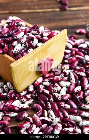 Violet avec des haricots de points dans une boîte en bois avec coeur. Avaler les haricots. Légumes pour une alimentation saine. Nourriture biologique. Régime Banque D'Images