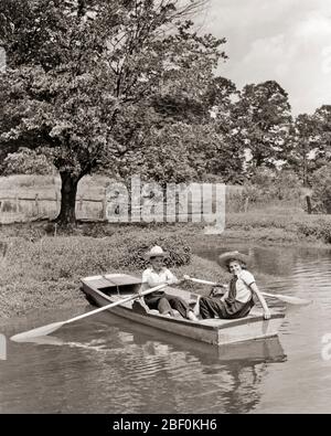 LES ENFANTS DES ANNÉES 1930 EN BARQUE POUSSANT DANS L'EAU POND GARÇON AVIRON FILLE À L'ARRIÈRE DU BATEAU TOURNÉ REGARDER LA CAMÉRA - B4104 HAR001 FRÈRES HARS SANTÉ RURALE HOME VIE COPIER ESPACE AMITIÉ DEMI-LONGUEUR HOMMES FRÈRES SŒURS TRANSPORT B&W ÉTÉ CONTACT BONHEUR AVENTURE GRAND ANGLE LOISIRS OARS BARQUE BUQUE SIBLING CONNEXION FACILE CHAPEAUX DE PAILLE COOPÉRATION JEUNES PRÉ-ADOLESCENCE PRÉ-ADOLESCENCE FILLE SAISON TOGETHNESS NOIR ET BLANC CAUCASIEN ETHNICITÉ HAR001 DÉMODÉE Banque D'Images