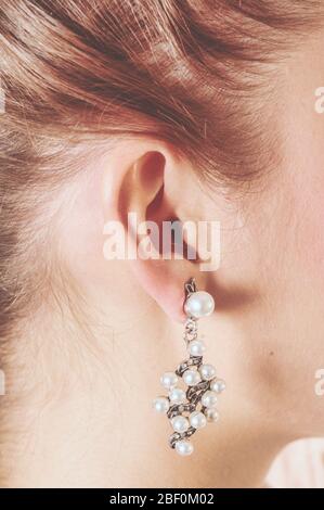 Photo de l'oreille tendre d'une fille portant un anneau d'oreille avec de nombreuses perles. Les couleurs vintage sont semblables à celles d'une photo ancienne. Banque D'Images