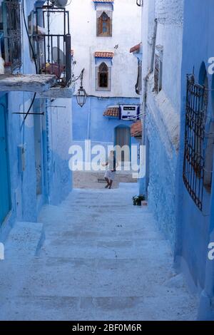 Chefchaouen, nord du Maroc, 10 juin 2016. Un jeune homme s'étend sur les marches d'une rue dans la vieille ville, la ville bleue. Banque D'Images