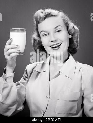 ANNÉES 1950 FEMME BLONDE SOURIANTE PERKY TENANT UN VERRE DE LAIT REGARDANT LA CAMÉRA - F3003 HAR001 HARS DEMI-LONGUEUR FEMMES PERSONNES CONFIANCE EXPRESSIONS B&W CONTACT YEUX BUG BONHEUR HUMOUR BOISSON BIEN-ÊTRE FLUIDE COMIQUE FIERTÉ PERKY COMÉDIE PROTÉINE LARGE-EYED JEUNE FEMME BOISSONS NOIR ET BLANC CAUCASIEN HAR001 VIEUX FAÇONNÉ Banque D'Images