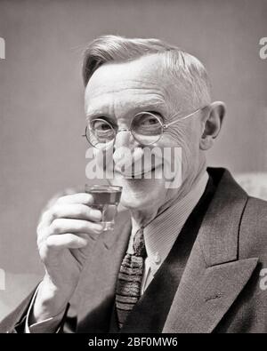 HOMME SENIOR DES ANNÉES 1930 SOURIANT LARGEMENT PORTANT DES LUNETTES REGARDANT L'APPAREIL PHOTO SUR LE POINT DE BOIRE UN VERRE DE WHISKY ALCOOL ALCOOL ALCOOL - F7407 HAR001 HARS STYLE DE VIE SATISFACTION TIR CÉLÉBRATION AÎNÉ STUDIO TOURNÉ SANTÉ COPIE ESPACE PERSONNES HOMMES RETRAITE CONFIANCE HOMME SENIOR LUNETTES EXPRESSIONS ADULTES SENIOR B&W CONTACT YEUX RETRAITÉ COSTUME ET CRAVATE BONHEUR HUMOUR VIEILLESSE OLDSTERS TÊTE ET ÉPAULES GAI OLDSTER SOURIRES COMIQUES AÎNÉS COMÉDIE LIQUEUR JOYEUSE VIEIL HOMME BOZE WHISKY NOIR ET BLANC CAUCASIEN ETHNICITÉ GRINNING HAR001 VIEUX FAÇONNÉ Banque D'Images